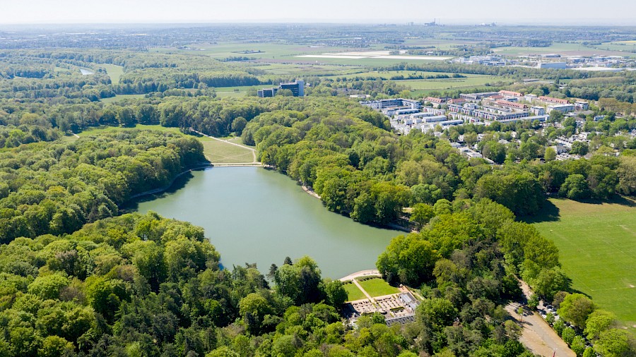 Blick über den Adenauer Weiher aus Richtung des Rhein-Energie-Stadions. Im Vordergrund der Club Astoria, rechts die Jahnwiesen. © Raimond Spekking / CC BY-SA 4.0 (via Wikimedia Commons) | Die Kölner Parkweiher – Holla der Waldsee