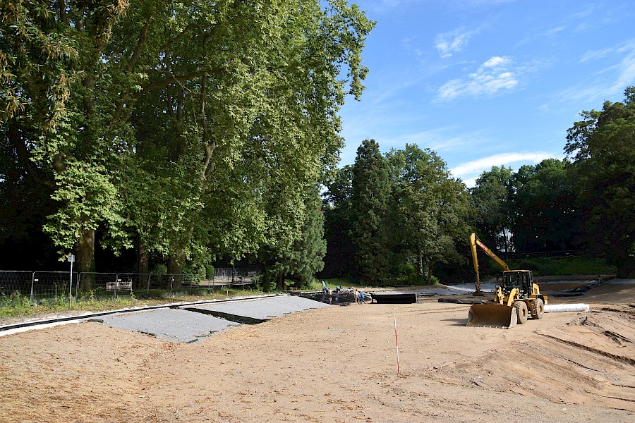 Baustellenfahrzeuge und Arbeiter im trocken gelegten Volksgartenweiher